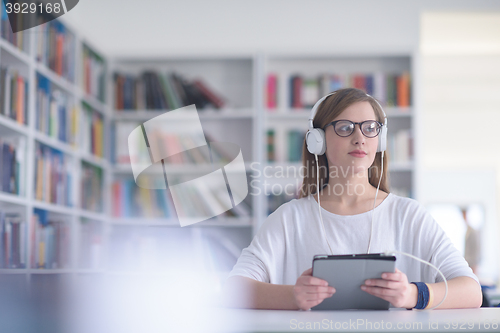 Image of female student study in library, using tablet and searching for 