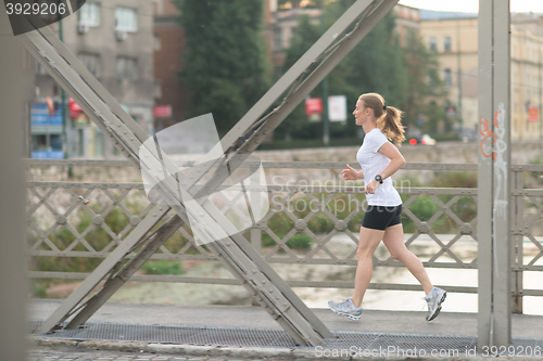 Image of sporty woman running  on sidewalk