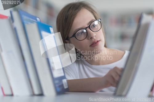 Image of portrait of famale student selecting book to read in library