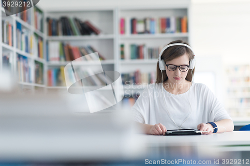 Image of female student study in library, using tablet and searching for 