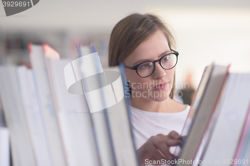 Image of portrait of famale student selecting book to read in library