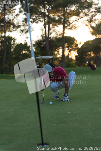 Image of golf player aiming perfect  shot on beautiful sunset