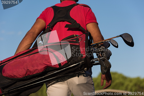 Image of close up of golfers back while   walking and carrying golf  bag