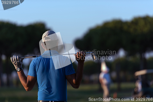 Image of golfer from back at course looking to hole in distance