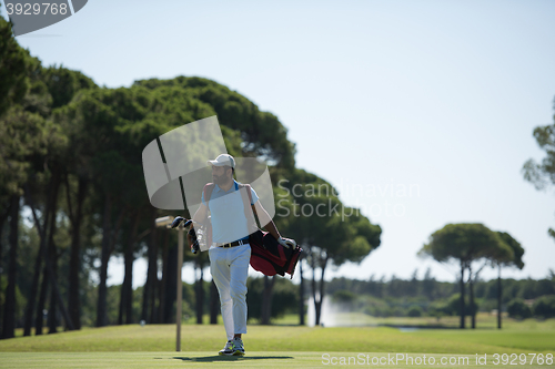 Image of golf player walking and carrying bag
