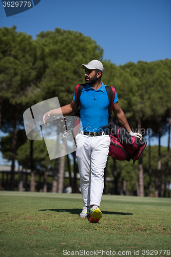 Image of golf player walking and carrying bag