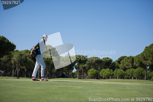 Image of golf player walking and carrying bag