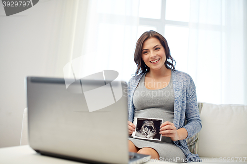 Image of happy pregnant woman with ultrasound image at home