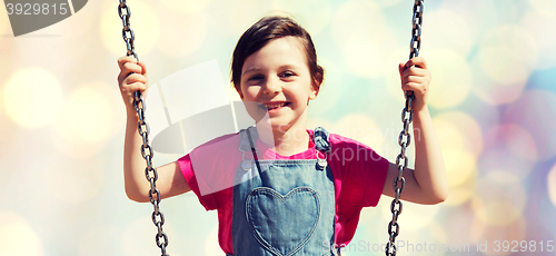 Image of happy little girl swinging on swing over lights