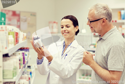 Image of pharmacist showing drug to senior man at pharmacy