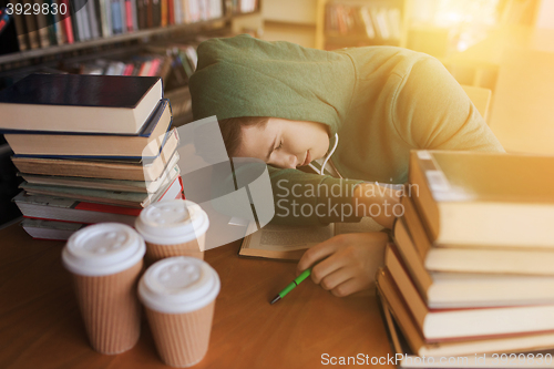 Image of tired student or man with books in library