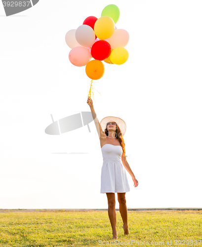 Image of smiling young woman in sunglasses with balloons