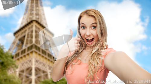 Image of happy woman taking selfie and showing thumbs up