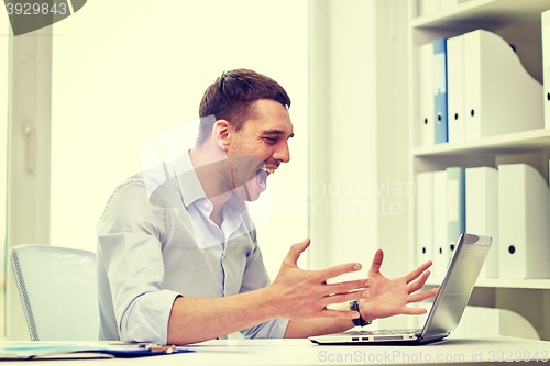 Image of angry businessman with laptop and papers in office