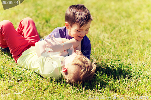 Image of happy little boys fighting for fun on grass