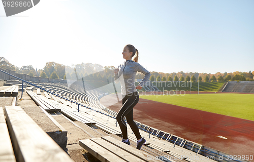 Image of happy young woman running upstairs on stadium