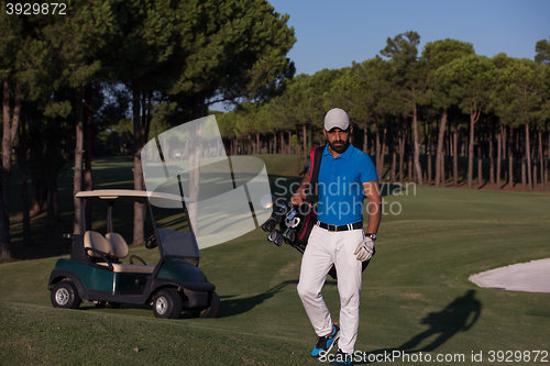 Image of golfer  walking and carrying golf  bag