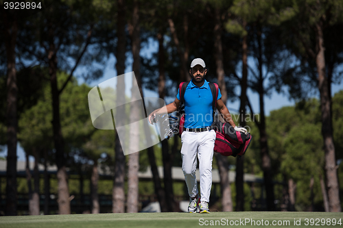 Image of golf player walking and carrying bag