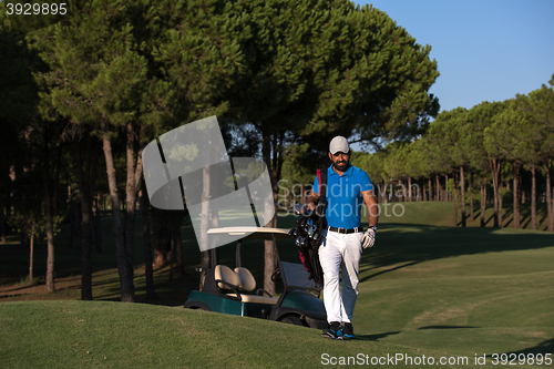 Image of golfer  walking and carrying golf  bag