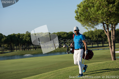 Image of golf player walking and carrying bag