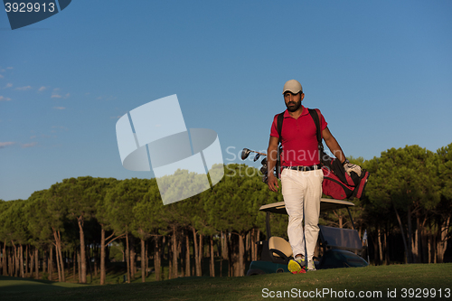 Image of golfer  walking and carrying golf  bag