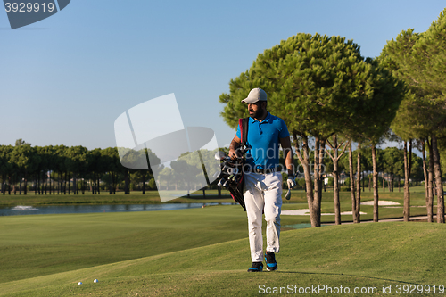 Image of golfer  walking and carrying bag