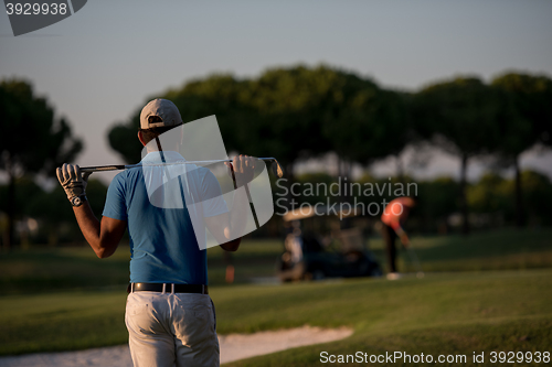 Image of golfer from back at course looking to hole in distance