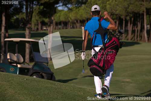 Image of golfer  walking and carrying golf  bag