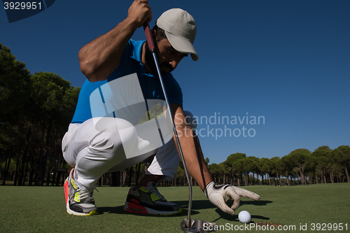 Image of man\'s hand putting golf ball in hole