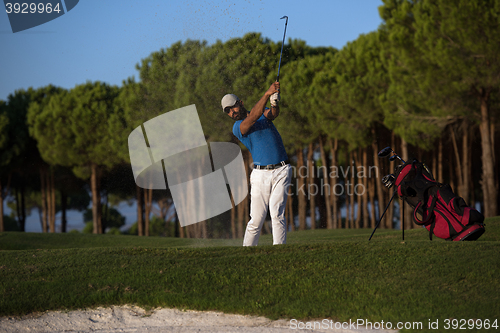 Image of golfer hitting a sand bunker shot on sunset