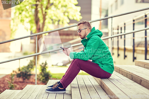 Image of young hipster man with smartphone in city