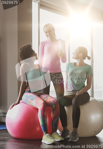 Image of group of smiling women with exercise balls in gym