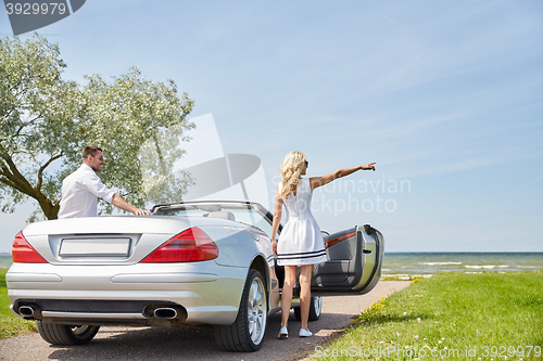 Image of happy man and woman near cabriolet car at sea