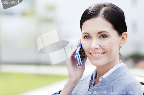 Image of young smiling businesswoman calling on smartphone
