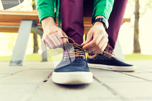 Image of close up of male hands tying shoe laces on street