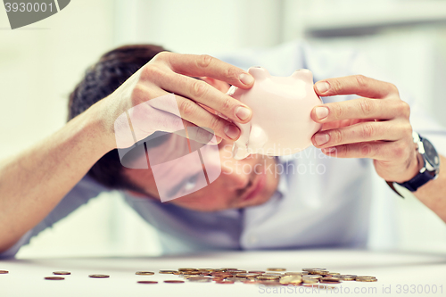 Image of businessman with piggy bank and coins at office