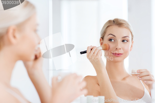 Image of woman with makeup brush and powder at bathroom