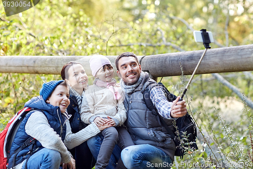 Image of happy family with smartphone selfie stick in woods