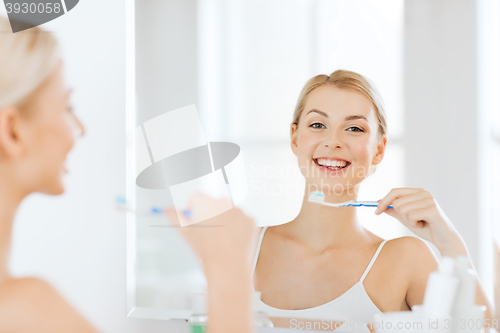 Image of woman with toothbrush cleaning teeth at bathroom