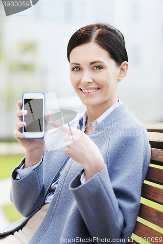 Image of young smiling businesswoman showing smartphone
