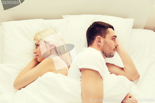 Image of unhappy couple lying in bed at home