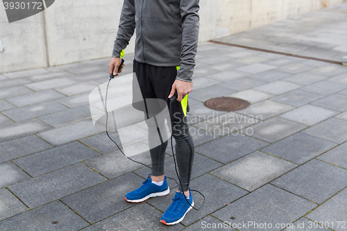 Image of close up of man exercising with jump-rope outdoors