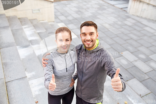 Image of smiling couple showing thumbs up on city street