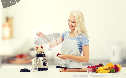 Image of smiling woman with blender preparing shake