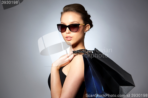 Image of happy woman in black sunglasses with shopping bags