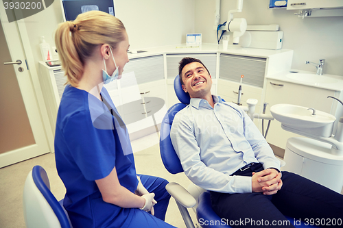 Image of happy female dentist with man patient at clinic