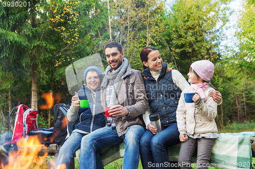 Image of happy family sitting on bench at camp fire