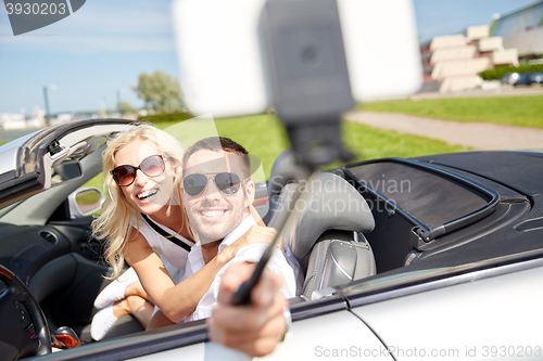 Image of happy couple in car taking selfie with smartphone