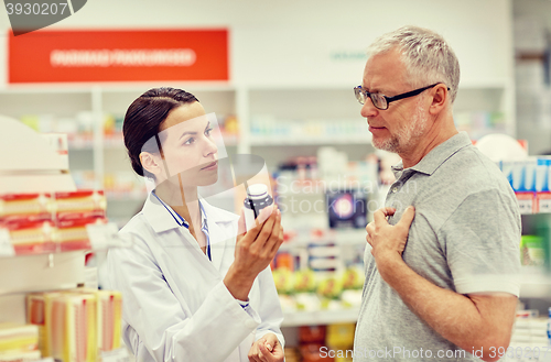 Image of pharmacist showing drug to senior man at pharmacy