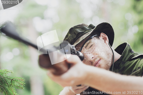 Image of young soldier or hunter with gun in forest